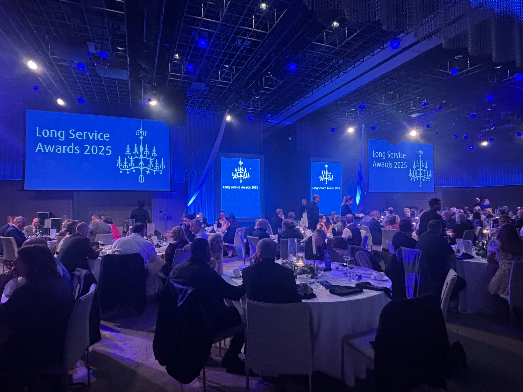 BOC Long Service Awards 2025 — the ballroom set for the ceremony dinner, with branded screens and guests at dressed round tables